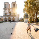 Morning view on the famous Notre-Dame cathedral with woman running on the square dispersing pigeons in Paris, France